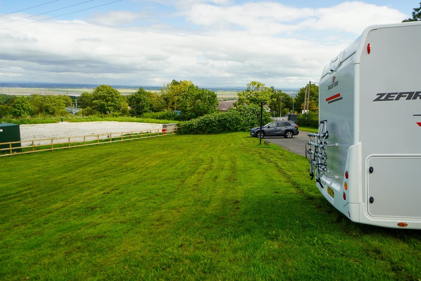 Camping-car près d’un espace herbeux dans un cadre rural.