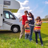 Famille heureuse devant leur camping-car garé dans un terrain de camping